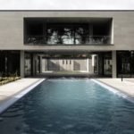 Elevated walkway bridges two parts of home divided by swimming pool